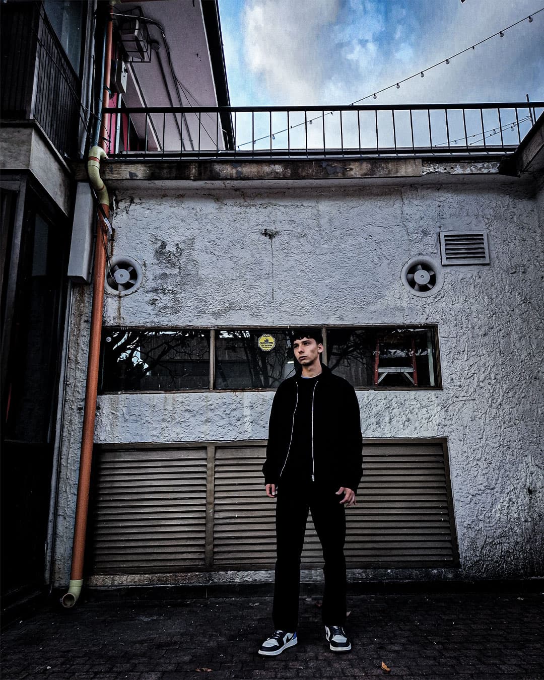 ANDY EMBER standing in an urban exterior setting